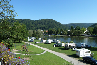 Campingplatz mit einer Reihe von weissen Wohnwägen. Direkt am Platz vorbei fliesst ein Fluss, der Neckar. Im Hintergrund ein bewaldeter Berg. Eberbach im Odenwald. | © Campingpark Eberbach