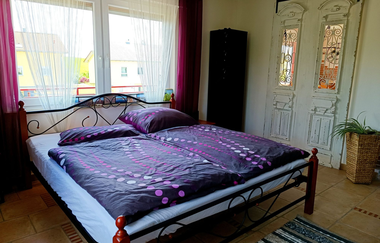 Schlafzimmer 2 mit lila Bettwäsche, Schrank und großen Fenstern | © Neckar-Zaber-Tourismus e.V.