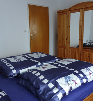 Schlafzimmer: Bett mit blauer Bettwäsche und ein großer Holzschrank mit Spiegel | © Neckar-Zaber-Tourismus e.V.