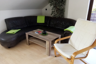 Wohnzimmer mit schwarzer Couch und Couchtisch, dazu ein Sessel