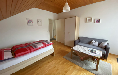 Schlafzimmer 1 mit Bett und grauer Couch mit kleinem Couchtisch | © Neckar-Zaber-Tourismus e.V.
