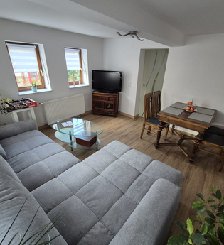 Wohnzimmer mit grauer Wohnlandschaft, Tisch mit 4 Stühlen | © Wolf