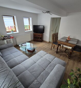 Wohnzimmer mit grauer Wohnlandschaft, Tisch mit 4 Stühlen | © Wolf