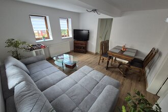 Wohnzimmer mit grauer Wohnlandschaft, Tisch mit 4 Stühlen | © Wolf