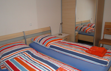 Schlafzimmer mit zwei Betten und Nachttischschränken. Ein großer Spiegelschrank rechts davon und ein Stuhl. | © Neckar-Zaber-Tourismus e.V.