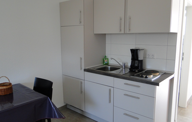 Küchenzeile bestehend aus mehreren weißen Schränken und Schubladen, davior steht ein Tisch mit Stuhl | © Neckar-Zaber-Tourismus e.V.