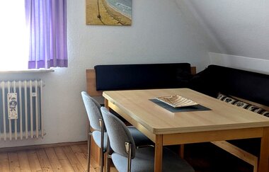 Zimmer mit Holzboden, lila Vorhängen, Bett und Tisch mit 2 Stühlen und Eckbank | © Bauer-Thorpe