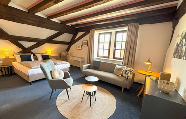 Innenansicht eines Zimmers der Herzogskelter mit Doppelbett, Kommode und kleinem Sofa | © Herzogskelter Güglingen