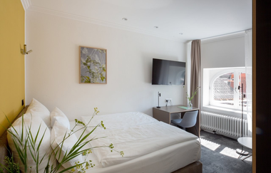 Hotelzimmer mit Doppelbett und kleinem Tisch mit Stuhl, sowie einem Flachbild-TV. | © Hotel Kredell