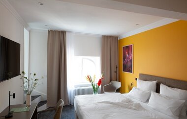 Hotelzimmer mit Doppelbett und Flachbild-TV. Vor dem TV befindet sich ein Tisch mit einen Stuhl. | © Hotel Kredell