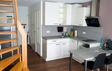 Blick auf die Küche: weiße Schränke und Schubladen, ein grauer Esstisch mit zwei Stühlen | © Neckar-Zaber-Tourismus