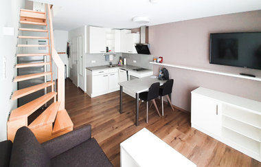 Blick auf die Treppe, die dunkelgraue Couch, die Küche und Wohnbereich mit Fernseher | © Neckar-Zaber-Tourismus e.V.