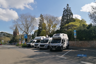 Vier Wohnmobile parken auf Stellplätzen an einer Schlossmauer, ein Behindertenparkplatz ist leer | © Jasmin Wolf