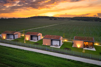Vogelperspektive-Blick auf die vier Chalets und dahinter liegende Weinberge bei Sonnenuntergang | © Weingut Becker, Malsch