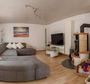 Wohnbereich mit großer grauer Couch, einem Flachbildfernseher und einem Kamin | © Neckar-Zaber-Tourismus e.V.