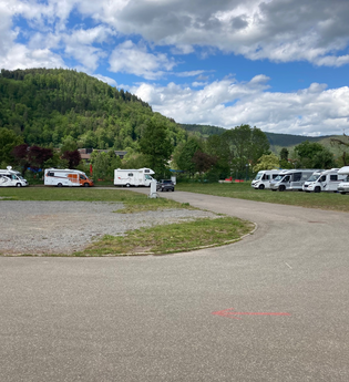 Eine geschotterte Fläche. Auf der linken Seite sowie auf der rechten Seite des Platzes stehen jeweils 4 Wohnmobile. Im Hintergrund ist ein bewaldeter Berg. Eberbach im Odenwald. | © Stadt Eberbach
