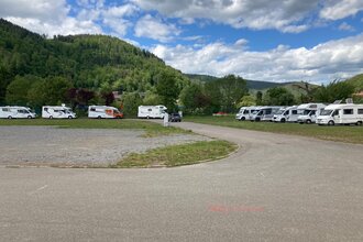 Eine geschotterte Fläche. Auf der linken Seite sowie auf der rechten Seite des Platzes stehen jeweils 4 Wohnmobile. Im Hintergrund ist ein bewaldeter Berg. Eberbach im Odenwald. | © Stadt Eberbach