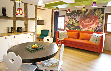 Wohnraum mit großer orangefarbener Couch und einem runden Hooltisch mit vier Stühlen | © Neckar-Zaber-Tourismus e.V.