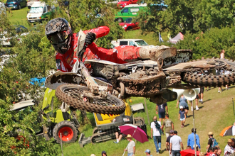 Ein Motorradfahrer in roter Kleidung mitten im Sprung, im Hintergrund Zuschauer | © Rainer Kengeter