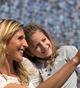 Eine Frau und ein Mädchen lächeln und zeigen in die Ferne vor einem unscharfen Hintergrund. | © Erlebnispark Tripsdrill