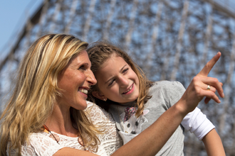 Eine Frau und ein Mädchen lächeln und zeigen in die Ferne vor einem unscharfen Hintergrund. | © Erlebnispark Tripsdrill