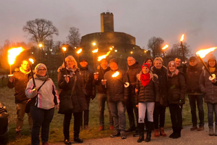 Menschen mit Fackeln vor der Burg Steinsberg
