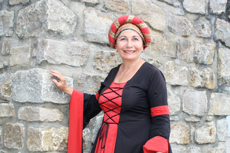 Burgfräulein in traditionellem Gewand vor Steinmauer | © Stadt Sinsheim