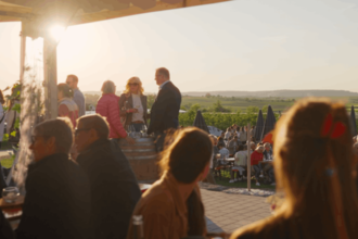Mehrere Menschen sind in einer Hütte auf einem Weingut zu sehen. Die Sonne scheint | © Moser Burgfeld