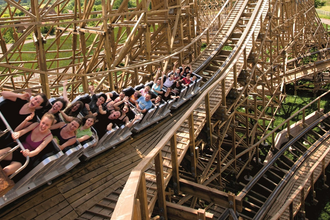 Menschen fahren in einer Holzachterbahn mit erhobenen Armen. | © Erlebnispark Tripsdrill