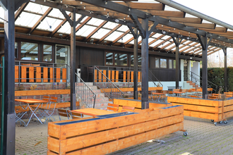 Terrasse mit Holztischen- und Stühlen