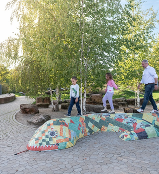 Kinder laufen über eine bunte Steinschlange im alla hopp!-Park