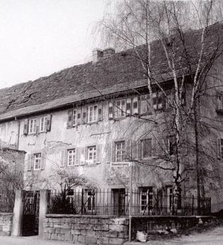 Schwarz-Weiß-Foto eines historischen Gebäudes hinter einer Steinmauer | © Unbekannt