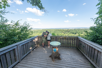Hölzerne Plattform mit zwei Personen und Blick auf den Wald