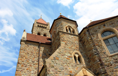 Die Fassade der Peterskirche aus gelbem vor blauem Himmel mit weißen Wolken.