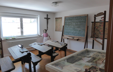 Blick auf ein historisches Klassenzimmer mit Holzbänken und Tafel | © Stadt Sinsheim