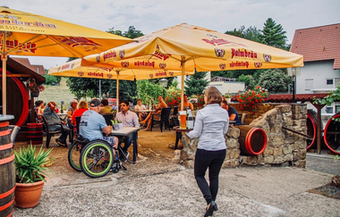 Gäste sitzen unter großen Sonnenschirmen im Außenbereich | © Zipse