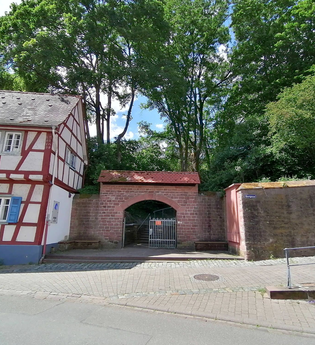 Ein überdachter Torbogen eingebettet zwischen einem Fachwerkhaus und einem Teil der alten Stadtmauer. | © Stadt Weinheim - Jasmin Wolf