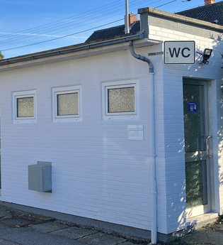 Kleines weißes Gebäude mit WC Schild