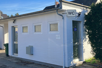 Kleines weißes Gebäude mit WC Schild