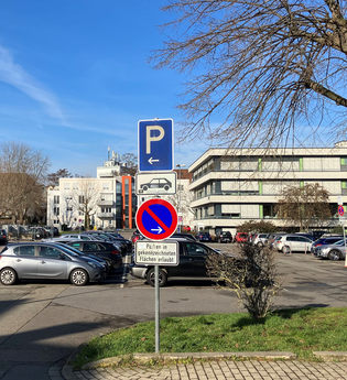 Parkplätze vor Gebäuden und Schildern im Vordergrund