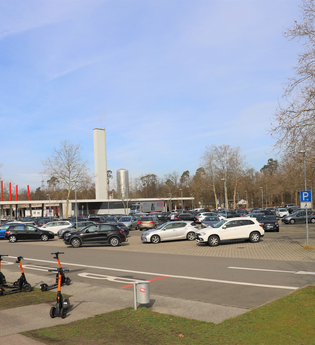 großer Parkplatz an der Astoria Halle mit Autos und E-Rollern