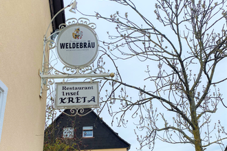 Schilder des Restaurants neben Baum