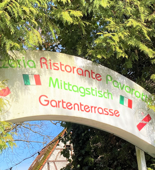 Schild "Pizzeria Ristorante Pavarotti" zwischen grünen Zweigen