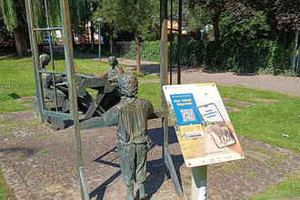 Schild der Weitersehen-Station in Hockenheim vor einer Statue in dem 3 Personen beim Tabakdrehen dargestellt sind | © Landratsamt Rhein-Neckar-Kreis