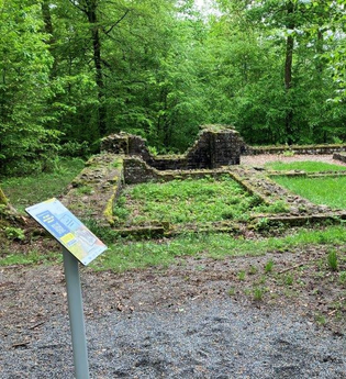 Im Vordergrund ist ein Schild für die Weitersehen App zu sehen und im Hintergrund die Mauern des Bodendenkmal der Villa Rustica im Wiesenbacher Wald | © Landratsamt Rhein-Neckar-Kreis