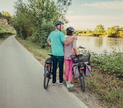 Ein Mann und eine Frau mit Fahrrädern stehen am Fluss. | © Touristikgemeinschaft HeilbronnerLand