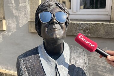 Eine Statue des Güglinger Kunstwerks "Persil bleibt Persil" mit einem roten Mikrofon mit der Aufschrift "Lauschtour" | © Neckar-Zaber-Tourismus e.V.