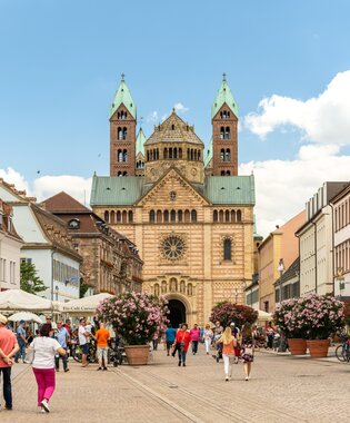 Fußgängerzone mit Menschen, Außengastronomie und Blumenarrangements vor der romanischen Kathedrale in Speyer | © Stadt Speyer, Foto Dominik Ketz