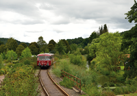 Roter Zug fährt auf Gleisen durch grünes Tal. | © Krebsbachtalbahn; Frank Jennerwein