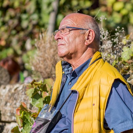 Mann lehnt an Weinbergmauer und genießt die Sonne